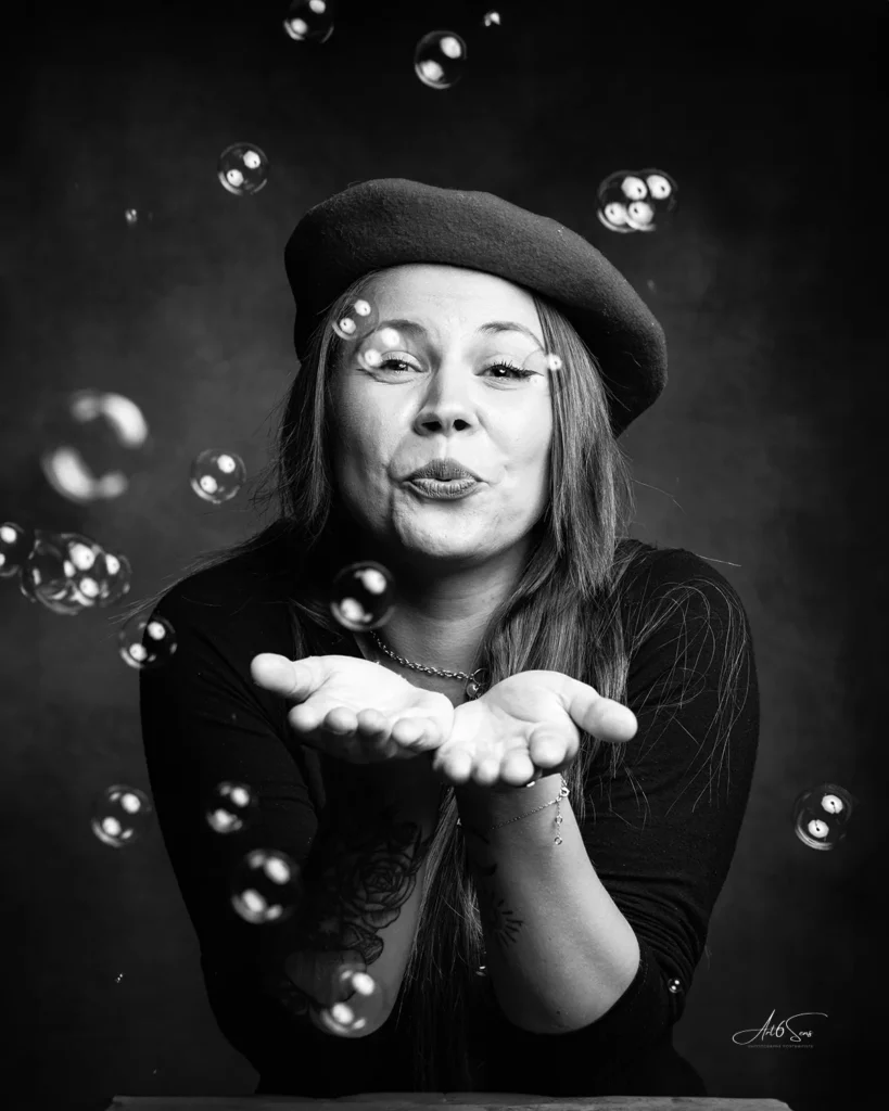 Portrait créatif d’une femme avec béret, bulles de savon, photo en noir et blanc.