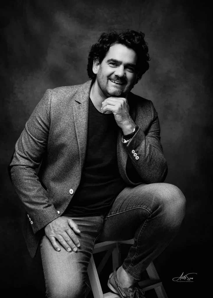 Portrait d’un homme en jean et veste, attitude décontractée, en studio noir et blanc.