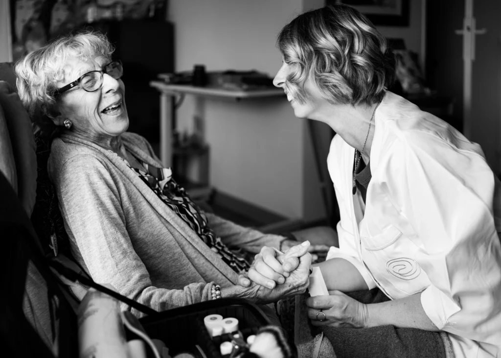 Reportage photo en entreprise – soignante et patiente partageant un moment de complicité, photographie en noir et blanc par Art6Sens.