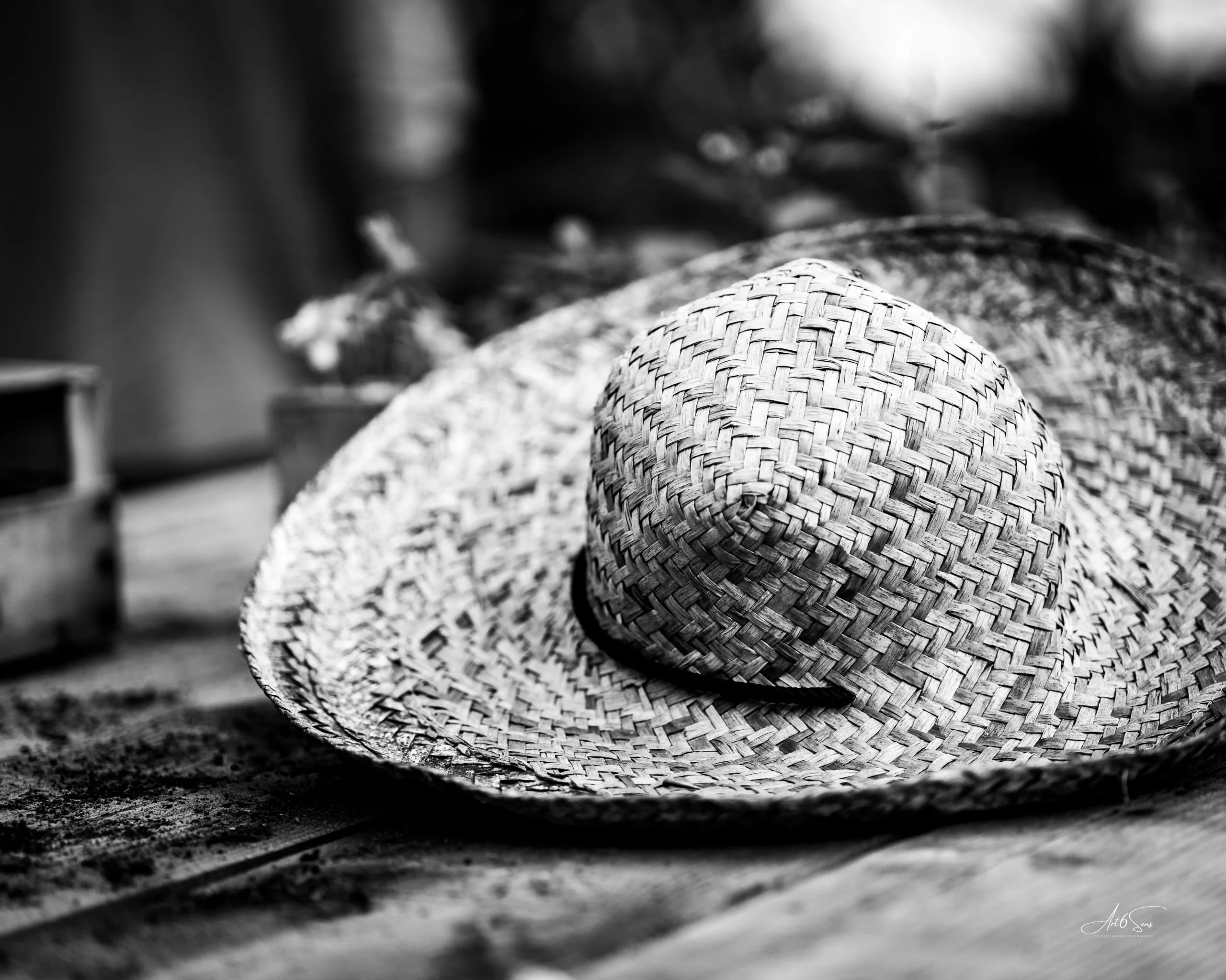 Chapeau en paille posé sur une table en bois, photographie en noir et blanc – détail artistique par Art6Sens, Portraitiste de France à La Teste.