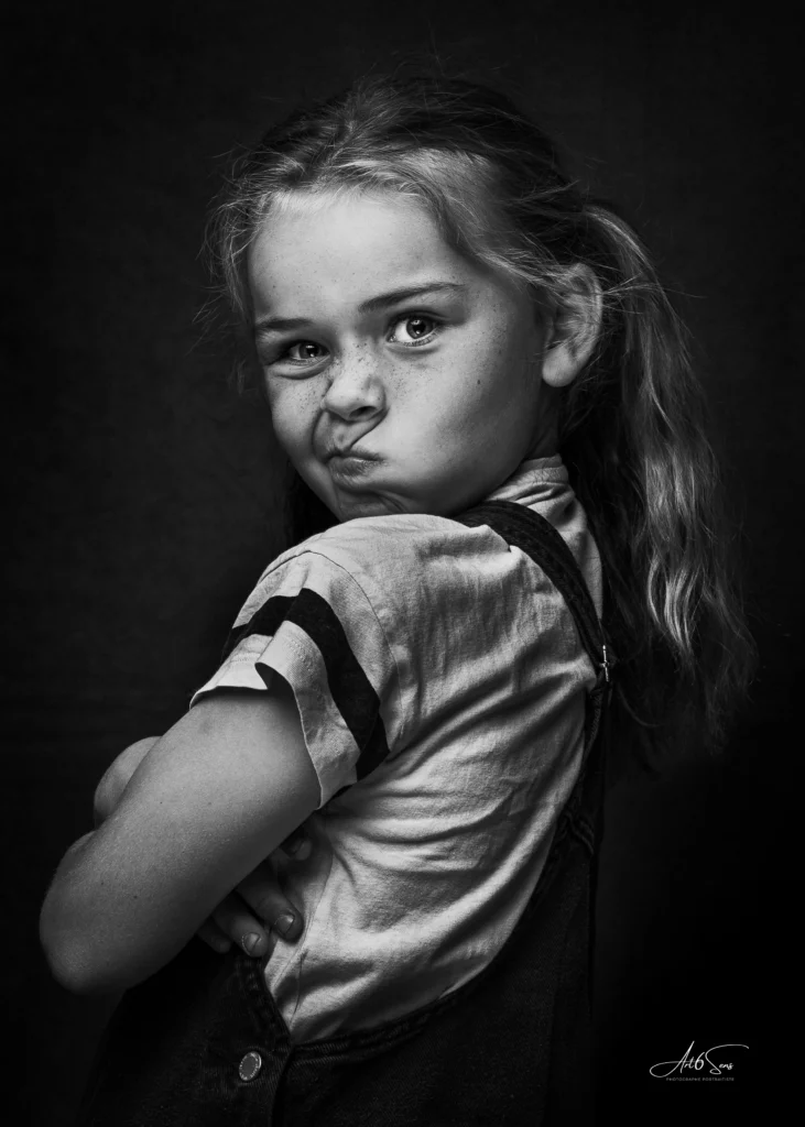 Portrait en noir et blanc d’une enfant expressive en studio.