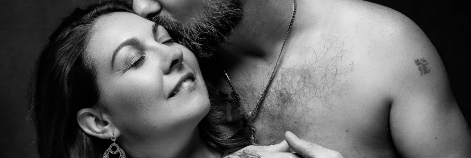 Portrait en noir et blanc d’un couple enlacé, l’homme torse nu embrassant tendrement la femme. Photographie intime et expressive signée Art6sens