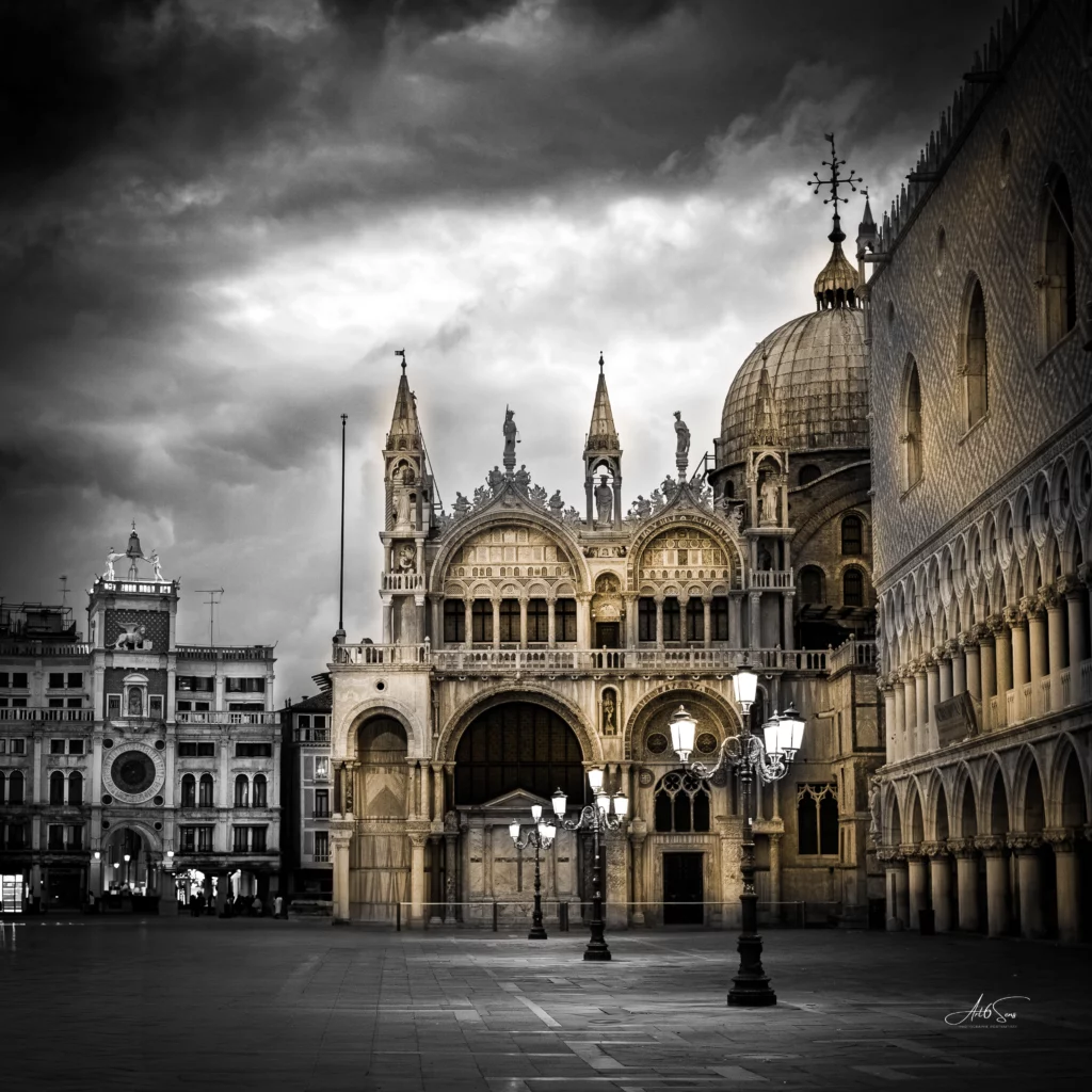 Photographie artistique de la place Saint-Marc à Venise au crépuscule, avec des reflets dorés sur la façade de la basilique, dans une ambiance calme et silencieuse.