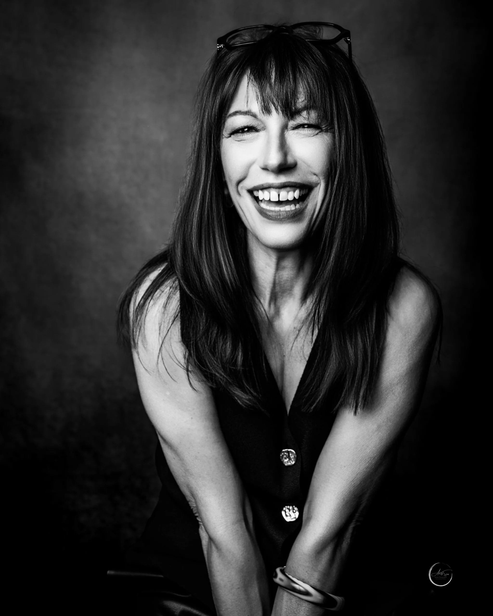 Portrait professionnel noir et blanc d'une femme entrepreneur souriante, lunettes rondes, studio Art6sens Bassin d'Arcachon